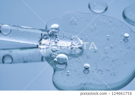 Pipette with serum on a blue background. Product texture. 124661758