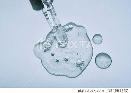 Pipette with serum on a blue background. Product texture. 124661767