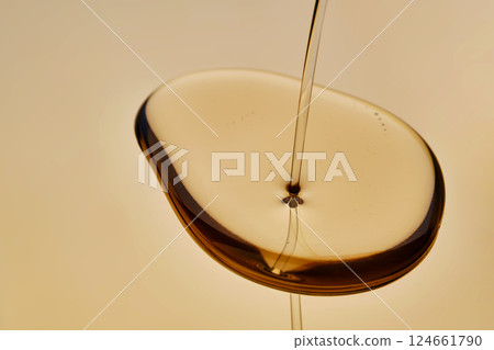 Texture of pouring cosmetic oil on a golden background. Texture of pouring cosmetic oil on a golden background. 124661790