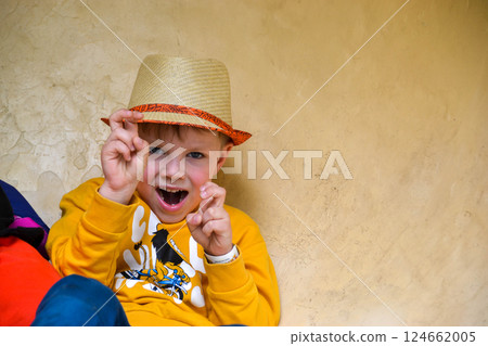 A toddler in a sun hat and yellow shirt is playfully making faces, bringing smiles and entertainment to the event with his fun and happy demeanor 124662005