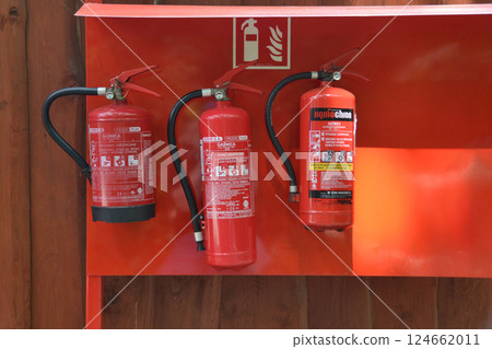 Three fire extinguishers filled with liquid solution are stored in a red plastic bottle on the shelving unit. It is important to keep them on the shelf for easy access in case of a fire emergency Three fire extinguishers filled with liquid solution are stored in a red plastic bottle on the shelving unit. It is important to keep them on the shelf for easy access in case of a fire emergency 124662011