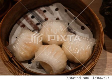 close up of four steamed Cantonese shrimp dumplings in a bamboo steamer 124662323
