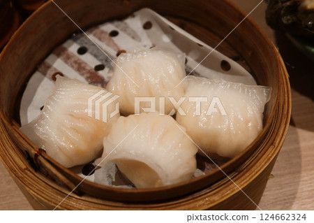 close up of four steamed Cantonese shrimp dumplings in a bamboo steamer 124662324
