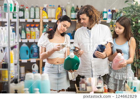 Family scanning bottles of cleaning products with phones in store Family scanning bottles of cleaning products with phones in store 124662829