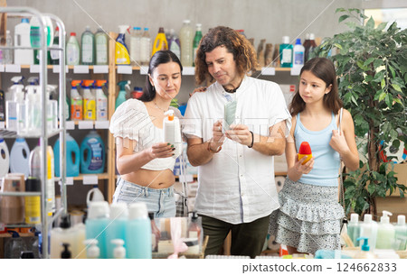Preteen girl with parents choosing tanning lotions in store 124662833