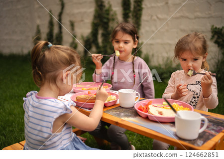 Three children enjoy a colorful meal outdoors on a sunny day Three children enjoy a colorful meal outdoors on a sunny day 124662851