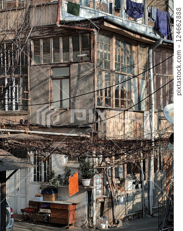 A close-up view of a rustic residential building with peeling paint, wooden windows, and clothes hanging outside. The image captures urban authenticity and daily life. 124662888