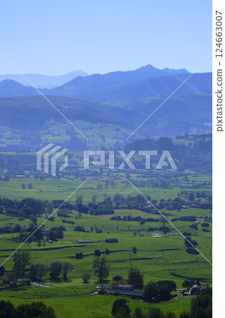 Breathtaking green valley opening up to blue mountains in rural landscape Breathtaking green valley opening up to blue mountains in rural landscape 124663007