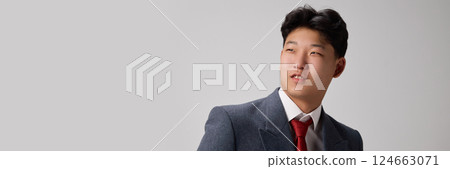 Banner. Photo of stylish young man in business suit looking aside with dreamy expression against grey background. 124663071