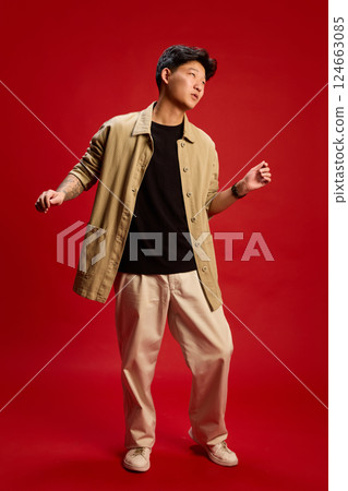Full length photo of confident young man in beige outfit dancing with cool vibe against red background. Concept of style Full length photo of confident young man in beige outfit dancing with cool vibe against red background. Concept of style 124663085