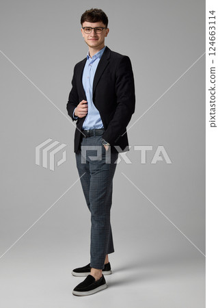 Full body photo of young professional posing confidently in suit, one hand in pocket against grey background. Concept of success 124663114