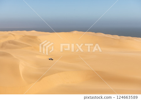 Lonely SUV car in Namibian dunes in Namib desert 124663589