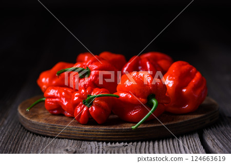 Wooden cutting board with heap of juicy red habanero peppers 124663619