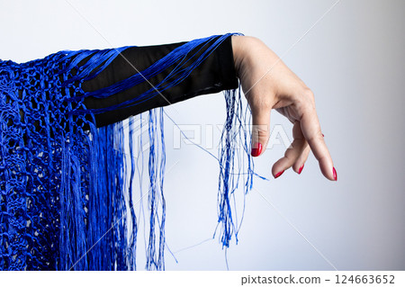 Female caucasian hand draped in blue fringe textile with red nails 124663652