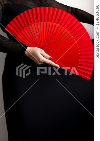 Female hand holding red fan against black background for flamenco dance concept Female hand holding red fan against black background for flamenco dance concept 124663660