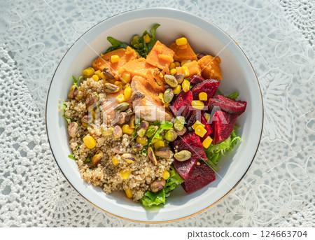 Top view of Delicious Quinoa Salmon Poke bowl garnished with Leaves salad, Beetroot, Sweet potato, Sweet corn and Pistachio. Top view of Delicious Quinoa Salmon Poke bowl garnished with Leaves salad, Beetroot, Sweet potato, Sweet corn and Pistachio. 124663704