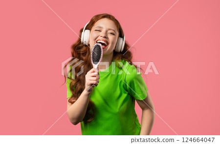 Woman singing, dancing with hair brush instead microphone on pink background. Lady having fun, listening to music, karaoke, dreams of being celebrity. 124664047