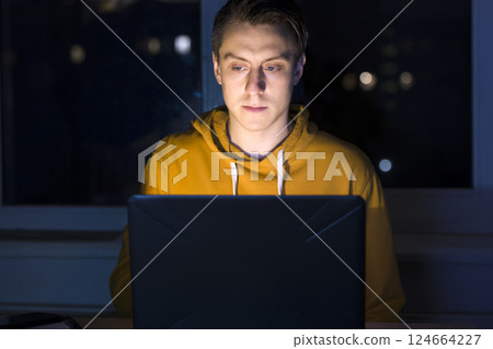 Man is working on a laptop at night. Man is working on a laptop at night. 124664227
