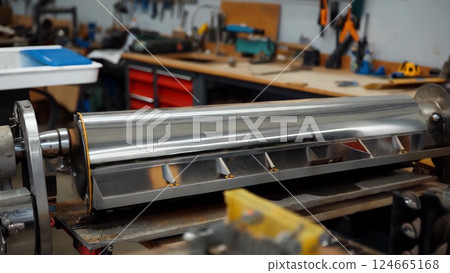 Polished Metal Cylinder Rotating in Workshop 124665168