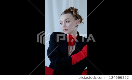 Studio portrait of a stylish woman wearing a black blazer, red rose choker necklace, and matching gloves, creating a bold and fashionable look 124666232