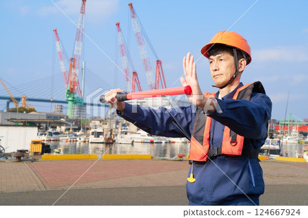A man in work clothes directing traffic at a port A man in work clothes directing traffic at a port 124667924