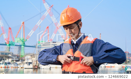 A man wearing a life jacket at a harbor 124669022