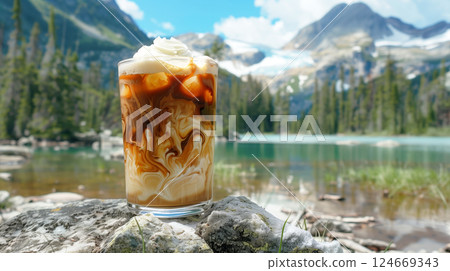 A tall glass of iced coffee with visible cream swirls, condensation on the glass, on scenic nature background. 124669343