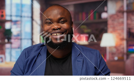 Teleworker at home office editing documents on his personal laptop, submitting reports and files before deadline. Black freelancer managing digital paperwork within the work platform. Camera b. 124669511