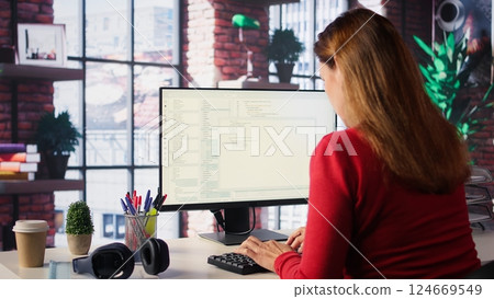 Woman engaging with an intelligent AI chatbot to complete work related tasks, working from loft apartment. Technology showcases machine learning and smart algorithms for productivity. Camera B. 124669549