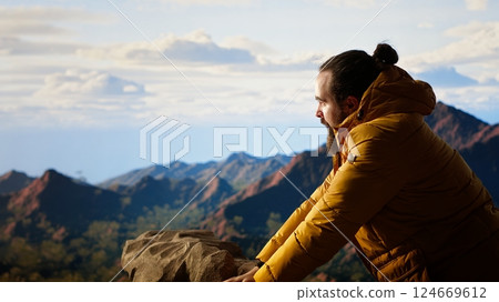 Nature lover on a mountain peak breathes in the crisp fresh air savoring the freedom and adventure. Traveler feeling proud of achievement, overlooking the valley with scenic landscape. Camera B. 124669612