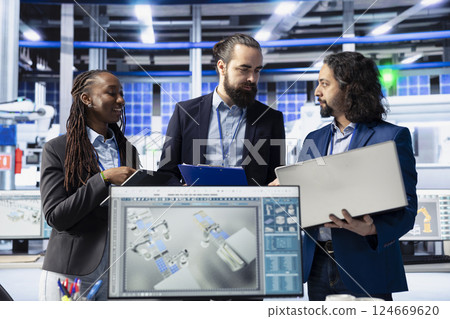 Engineering team in solar panel plant adjusting robotic machinery settings through computer software. Teamworking photovoltaics factory colleagues diagnosing gear performance issues Engineering team in solar panel plant adjusting robotic machinery settings through computer software. Teamworking photovoltaics factory colleagues diagnosing gear performance issues 124669620