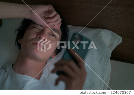 Men watching smartphones in bed Men watching smartphones in bed 124670507