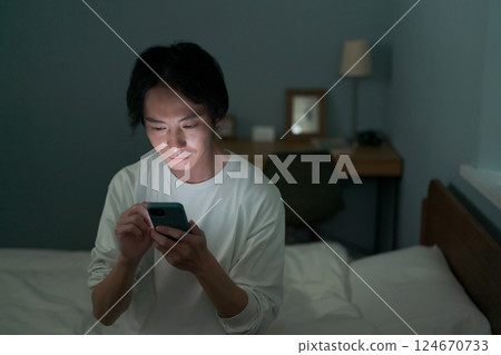 一名男子在黑暗的房間裡操作智慧型手機 124670733