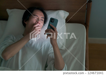 一名男子在床上使用智慧型手機 124671041