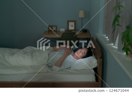 A man using a smartphone in bed 124671044