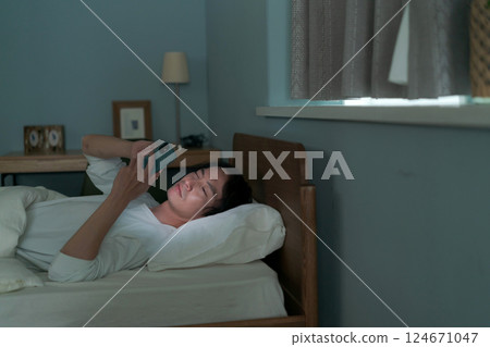 A man using a smartphone in bed 124671047