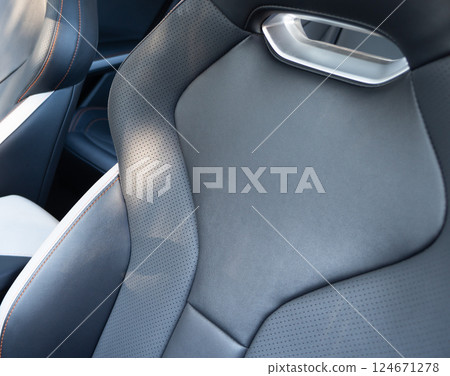 Car black leather interior. Part of black leather car seat details with white stitching. Interior of prestige car. Comfortable perforated leather seats. Perforated leather. Car black leather interior. Part of black leather car seat details with white stitching. Interior of prestige car. Comfortable perforated leather seats. Perforated leather. 124671278