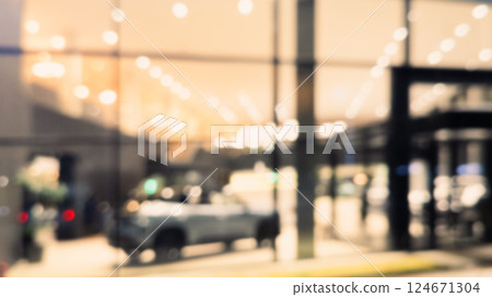 Blurred background with car dealership exterior. Abstract blurred photo of modern building motor showroom. Blur car show room office bokeh lights. Automobile retail shop 124671304