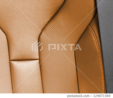 Car brown leather interior. Part of brown leather car seat details with white stitching. Interior of prestige car. Comfortable perforated leather seats. Perforated leather. 124671369