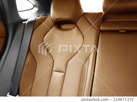 Back passenger brown seats in modern luxury car. Brown perforated leather with white stitching. Car details. Leather comfortable seats. Car interior details 124671372