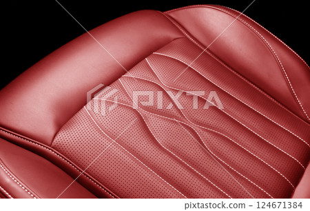 Car red leather interior. Part of red leather car seat details with white stitching. Interior of prestige car. Comfortable perforated leather seats. 124671384