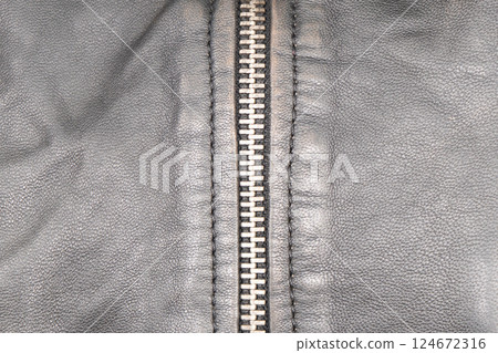 Macro shot of zipper on black leather texture background with stitching. Close-up of black leather material Macro shot of zipper on black leather texture background with stitching. Close-up of black leather material 124672316