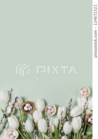 Creative Easter flat lay featuring white tulips, speckled pastel eggs in nests, pussy willow branches, and soft feathers on mint green background. space for festive advertisements Creative Easter flat lay featuring white tulips, speckled pastel eggs in nests, pussy willow branches, and soft feathers on mint green background. space for festive advertisements 124672321