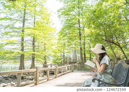 A woman taking a break in a park with fresh green leaves A woman taking a break in a park with fresh green leaves 124672599