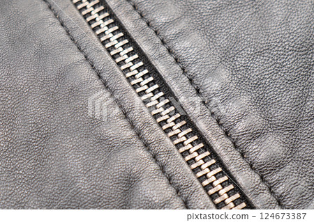 Macro shot of zipper on black leather texture background with stitching. Close-up of black leather material Macro shot of zipper on black leather texture background with stitching. Close-up of black leather material 124673387
