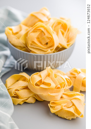 Italian pasta tagliatelle. Uncooked noodle pasta on gray background. 124673652