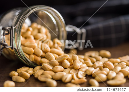 Roasted salted peanuts in jar on wooden table. 124673657