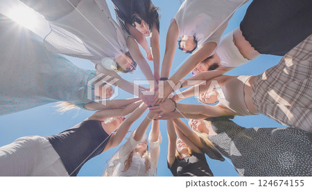 High school students unite in a circle, celebrating friendship and achievements under a sunny summer sky 124674155