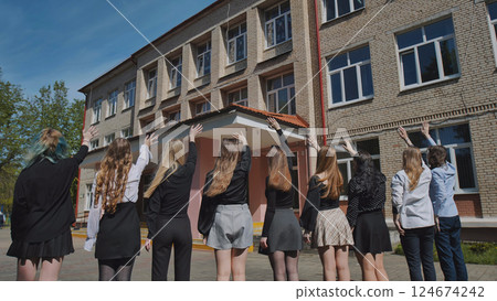 Group of students waving goodbye to their school on their last day, celebrating the end of the academic year 124674242