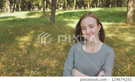 Portrait of confident businesswoman posing with crossed arms in green park during sunny summer day Portrait of confident businesswoman posing with crossed arms in green park during sunny summer day 124674281